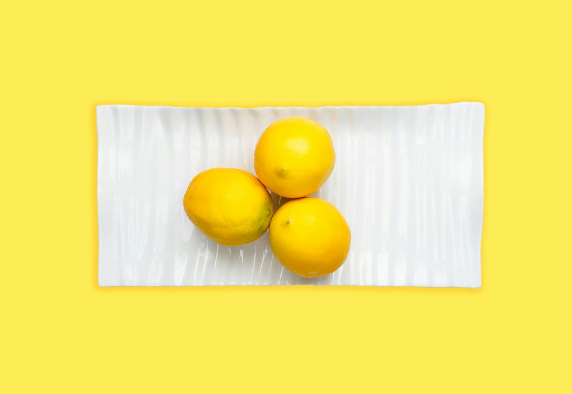 Hand holding a fresh lemon against a vivid yellow background, symbolizing renewal and fresh perspective