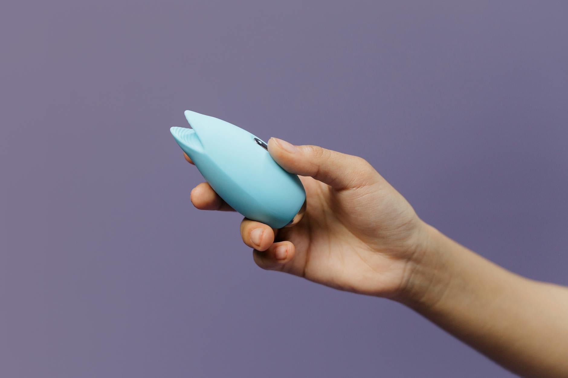 A blue silicone lemon vibrator held in hand against a purple background, showcasing suction technology design