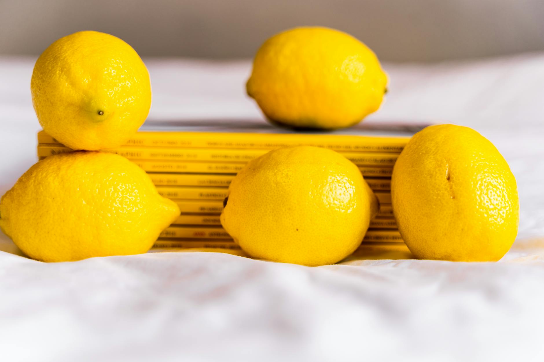Fresh yellow lemons with books on a white surface, symbolizing natural vitality and refreshment